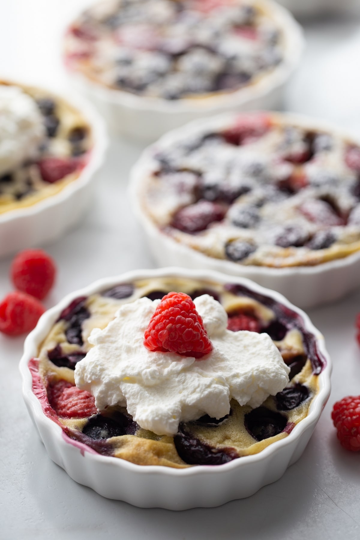 Enjoy the taste of summer with this mixed berry and cherry clafoutis. This dessert features ripe cherries and berries baked into a creamy custard. cherry clafoutis with whipped cream