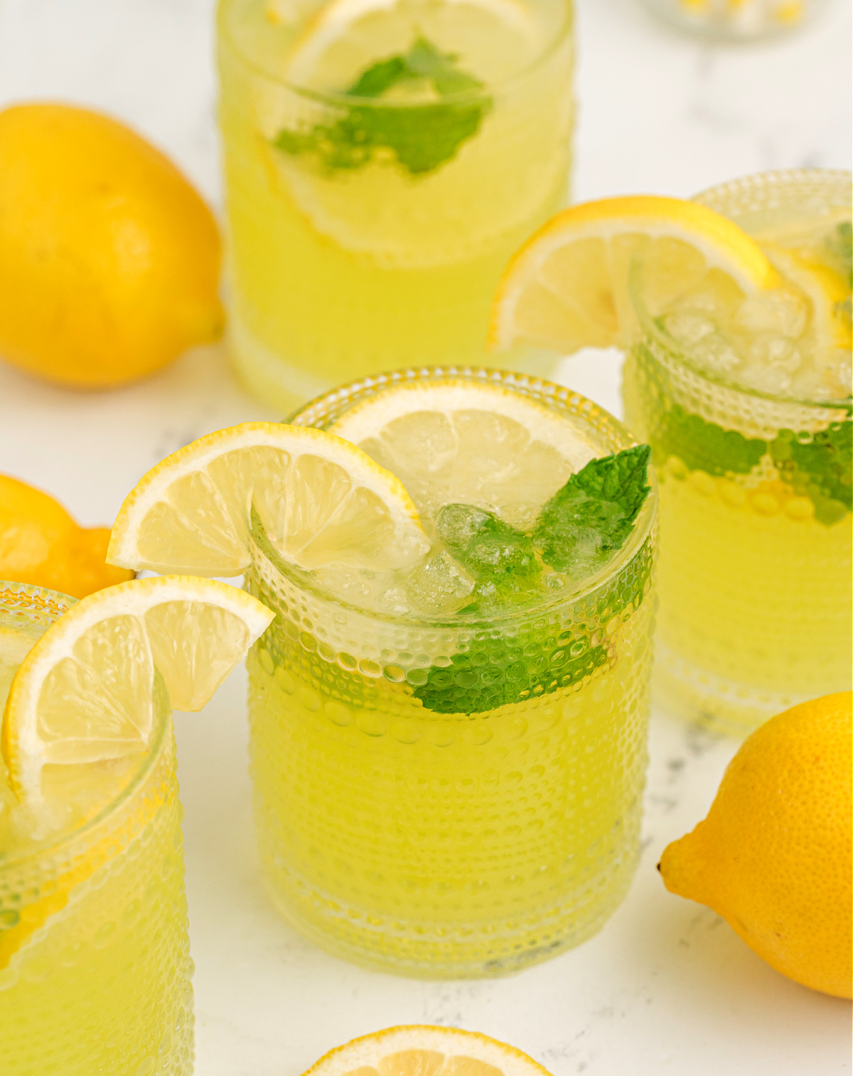 simple lemon and limoncello cocktail lemonade limoncello cocktail with crushed ice, mint sprig, and a lemon wedge
