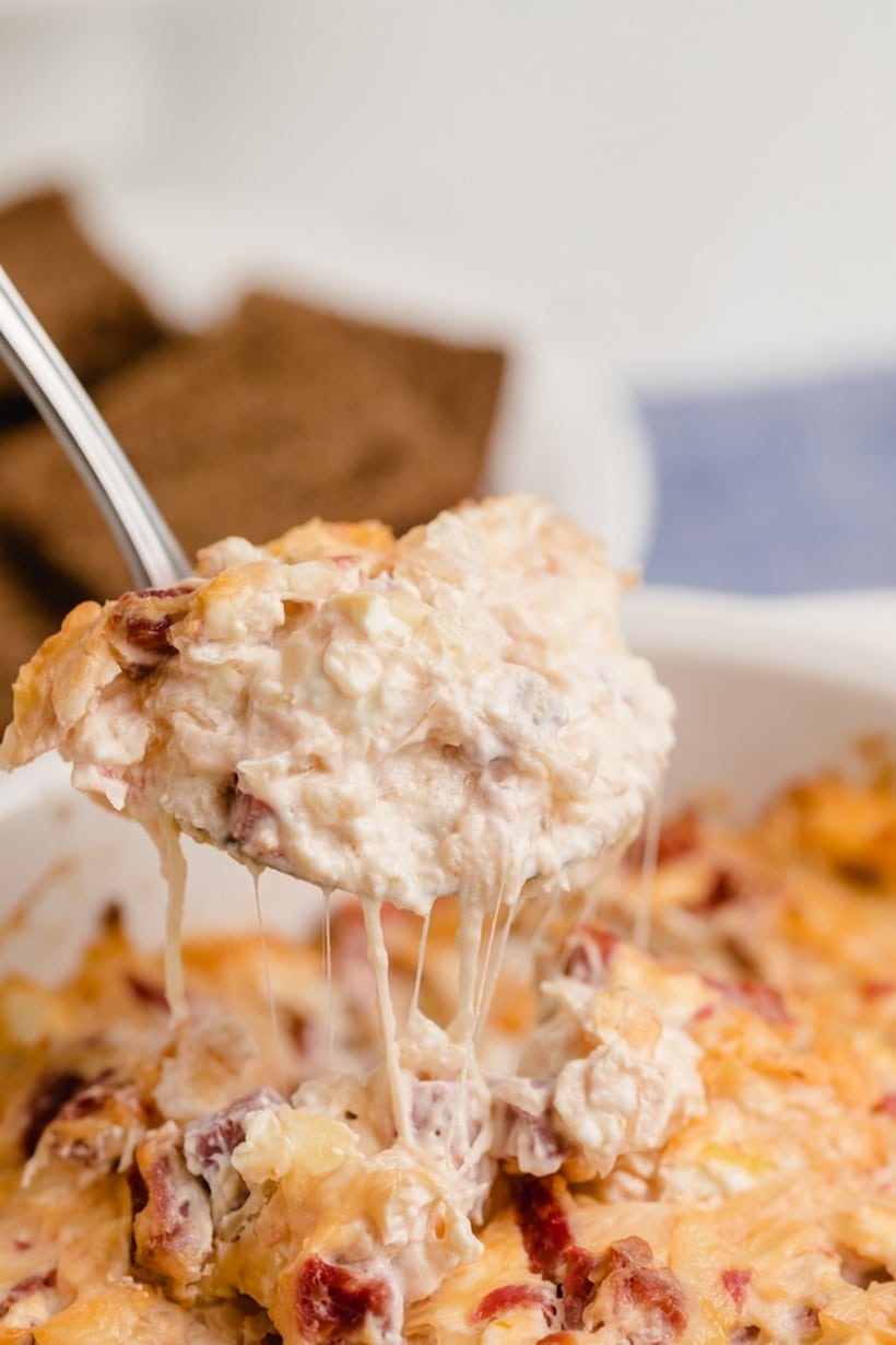 Close-up of Reuben dip being scooped from a baking dish with a slice of bread.