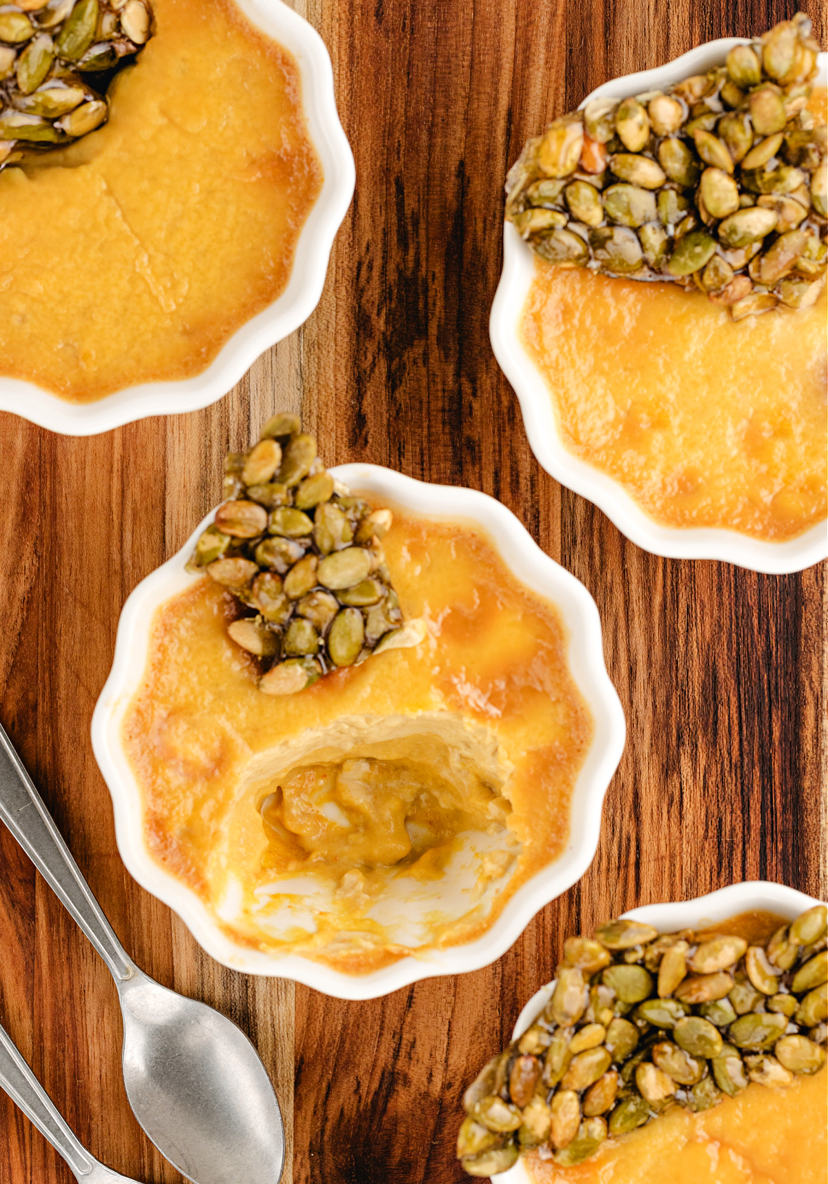Pumpkin Chai Pots de Crème with a spoonful taken out to show the creamy chai-spiced pumpkin custard beneath the brittle topping.