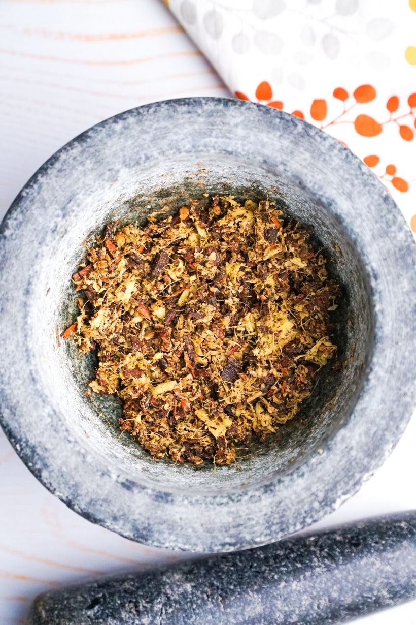 Coarsely crushed spices in a mortar and pestle for making Chai Eggnog.