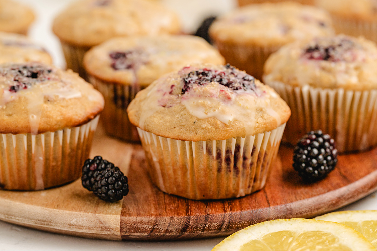 glazed blackberry lemon muffins with oats bakery-style lemon blackberry muffins topped with coarse sugar and glaze on a wooden board