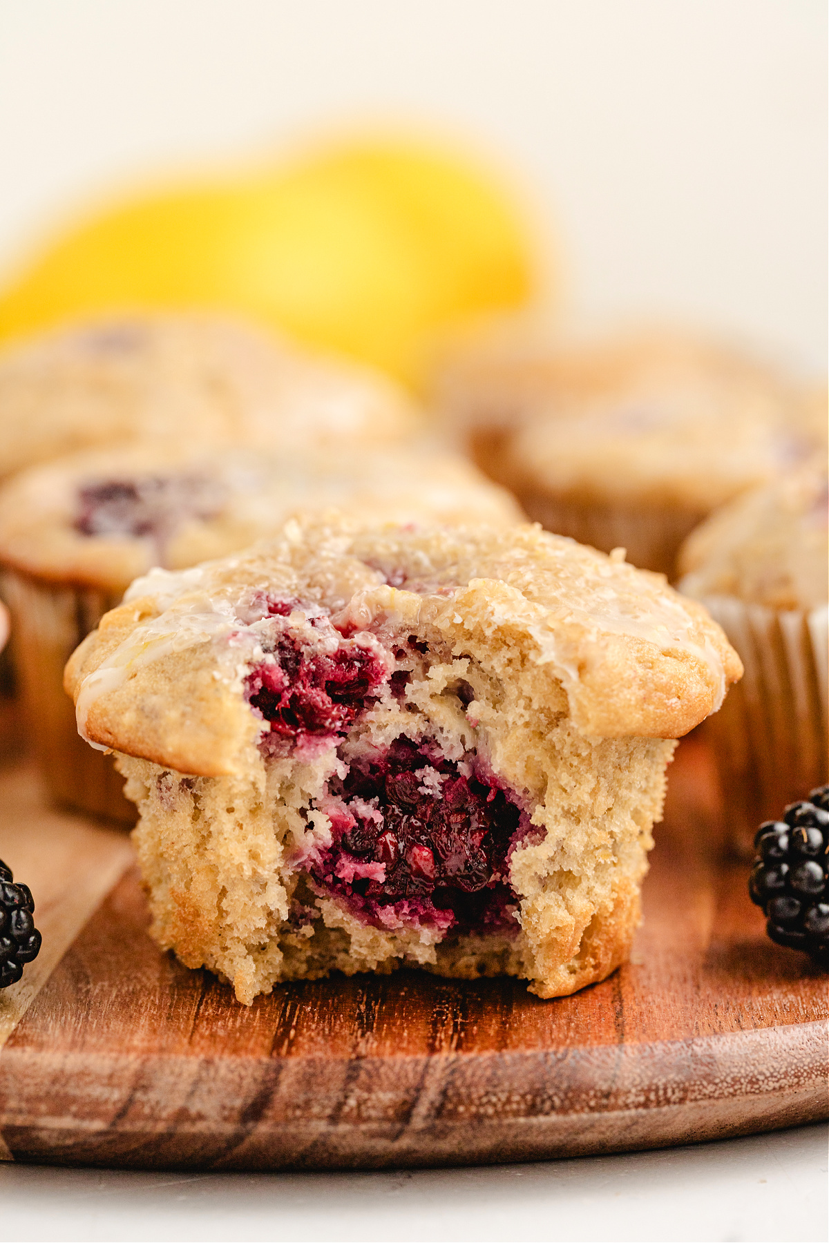 muffin with blackberries and lemon glaze, close view close-up of soft oat muffin with whole blackberries baked inside and light glaze on top