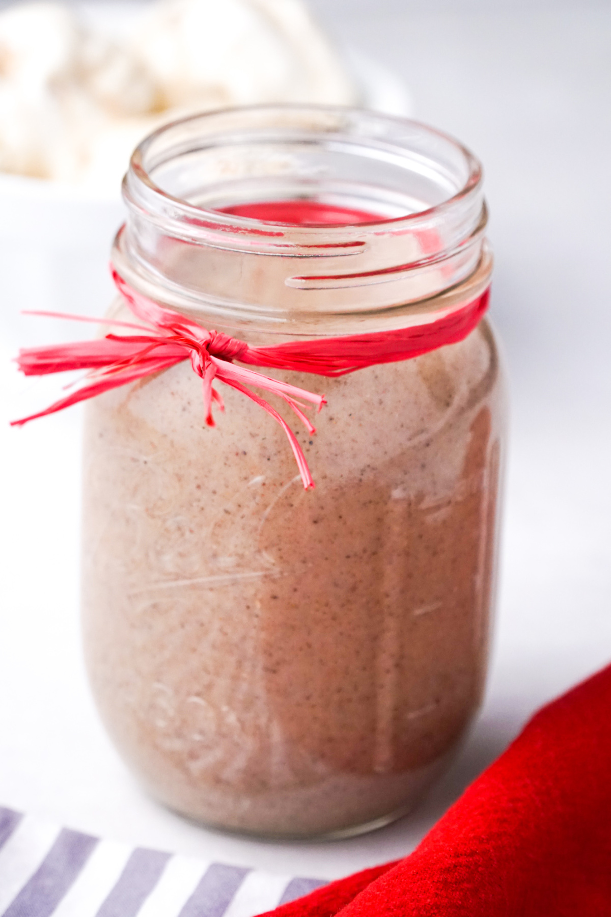 Jar of homemade chai-spiced syrup tied with a red ribbon