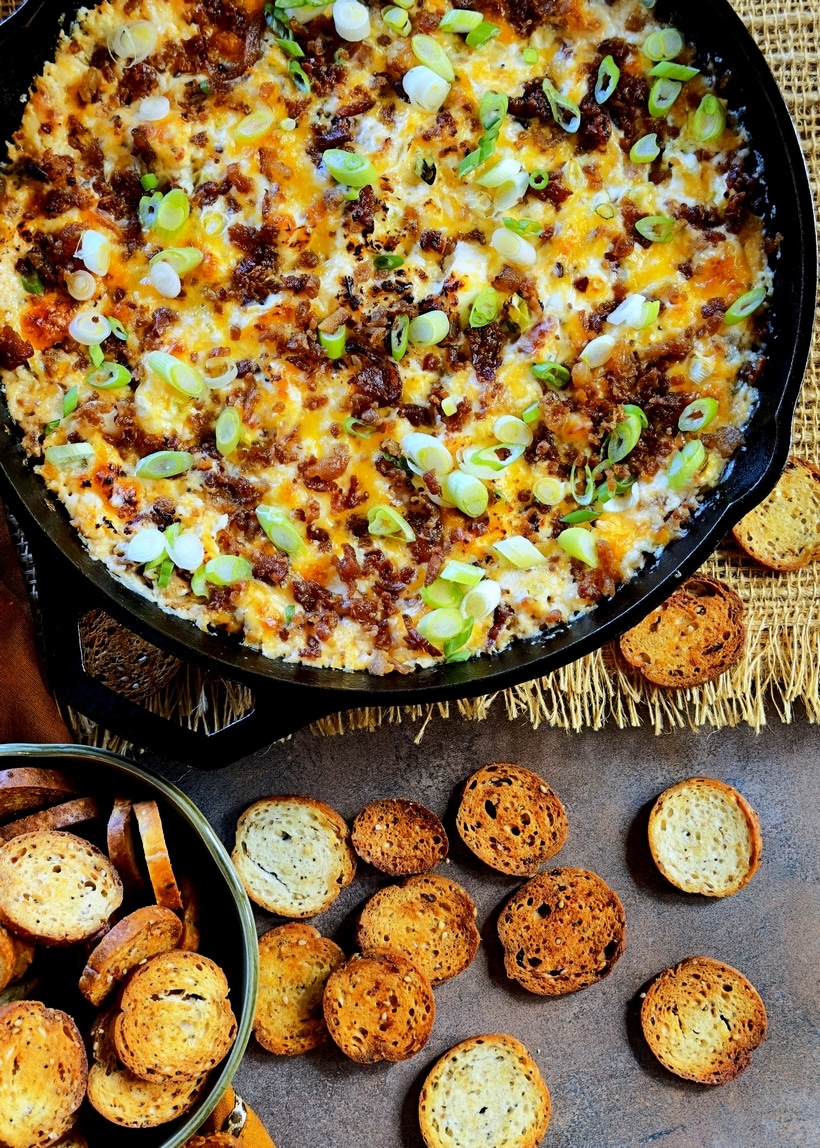 Overhead view of hot bacon dip bubbling in a cast iron skillet.