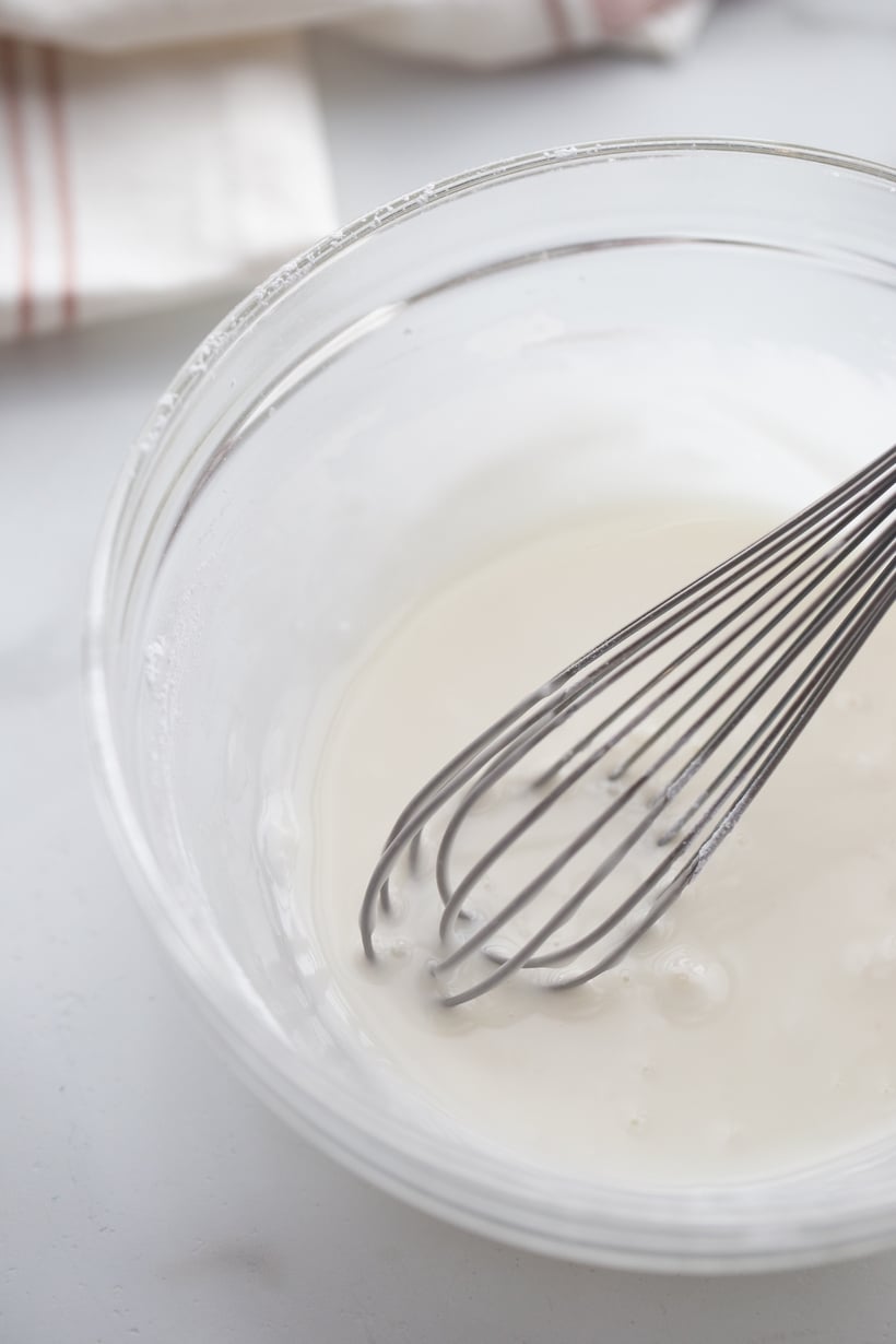 Cornmeal-Blueberry Drop Scones making the icing A small bowl of lime icing with a whisk, showing the smooth, drizzling consistency.