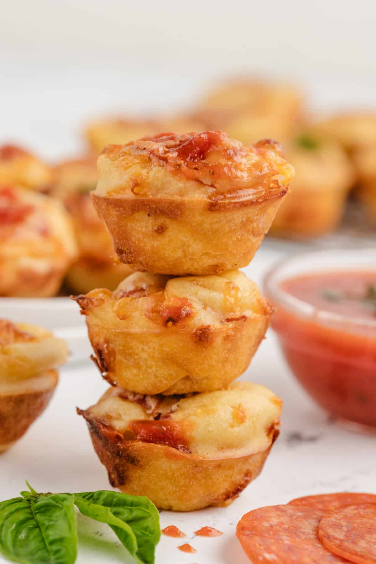 Three golden, cheesy pepperoni pizza puffs stacked on top of each other, showing their fluffy texture and crispy edges.