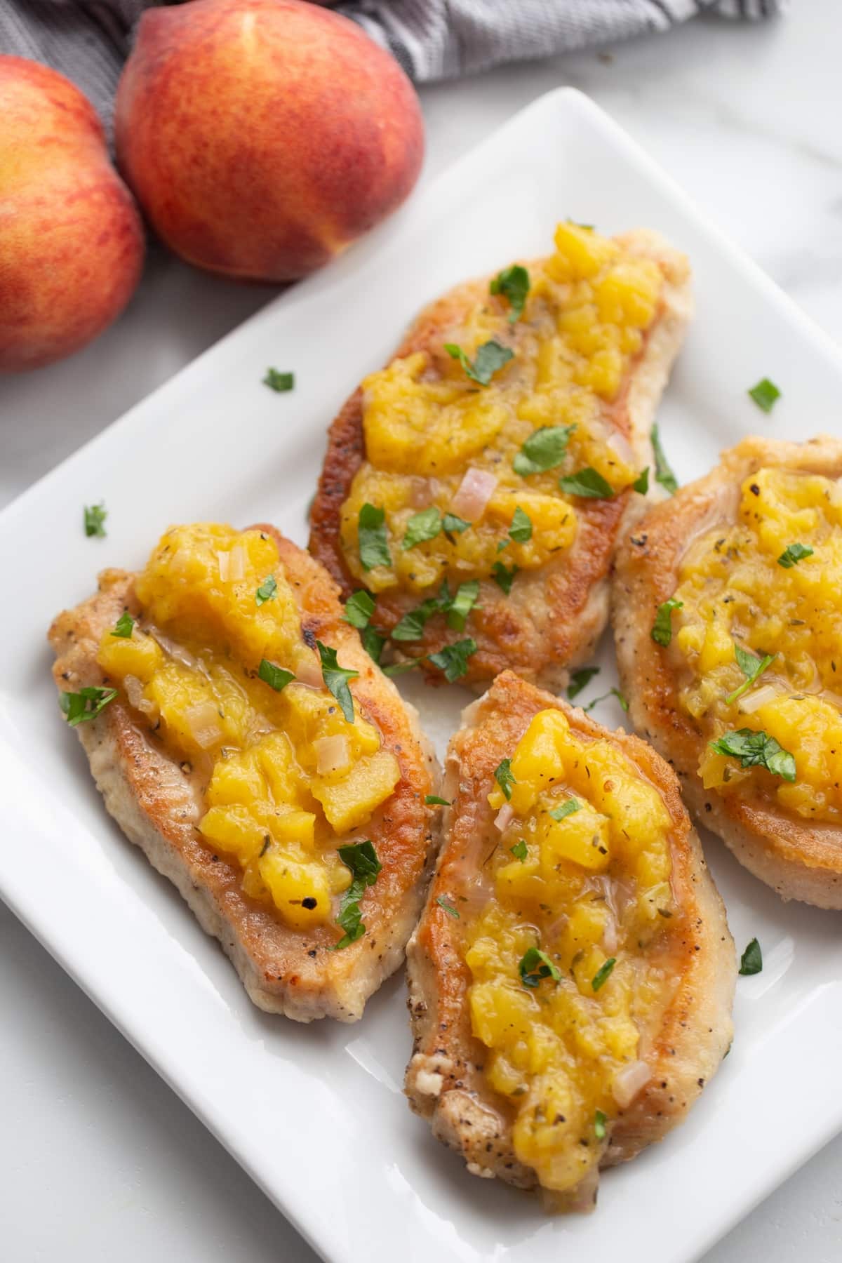 Peach chutney pork chops plated and ready to serve Overhead view of peach chutney pork chops served on a white plate