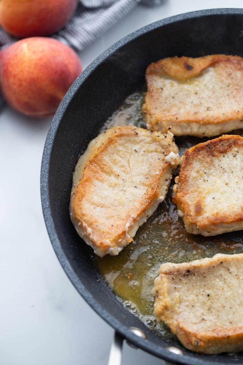 Crispy pork chops searing in a hot skillet Golden pan-seared pork chops cooking in a skillet