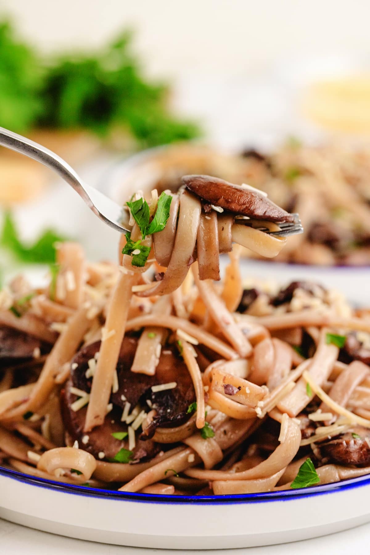 Garlic Parmesan mushroom pasta lifted on a fork with fresh parsley