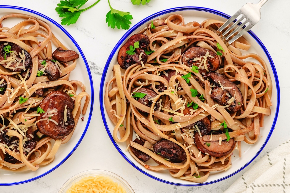 Mushroom fettuccine recipe served on two plates with Parmesan and parsley