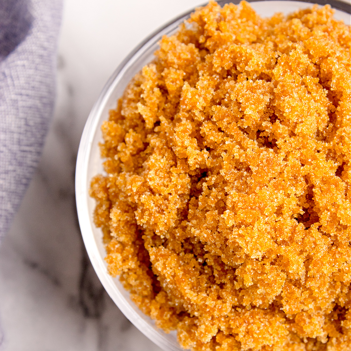 A close-up overhead view of homemade brown sugar in a bowl, showing the grainy caramel-colored crystals.