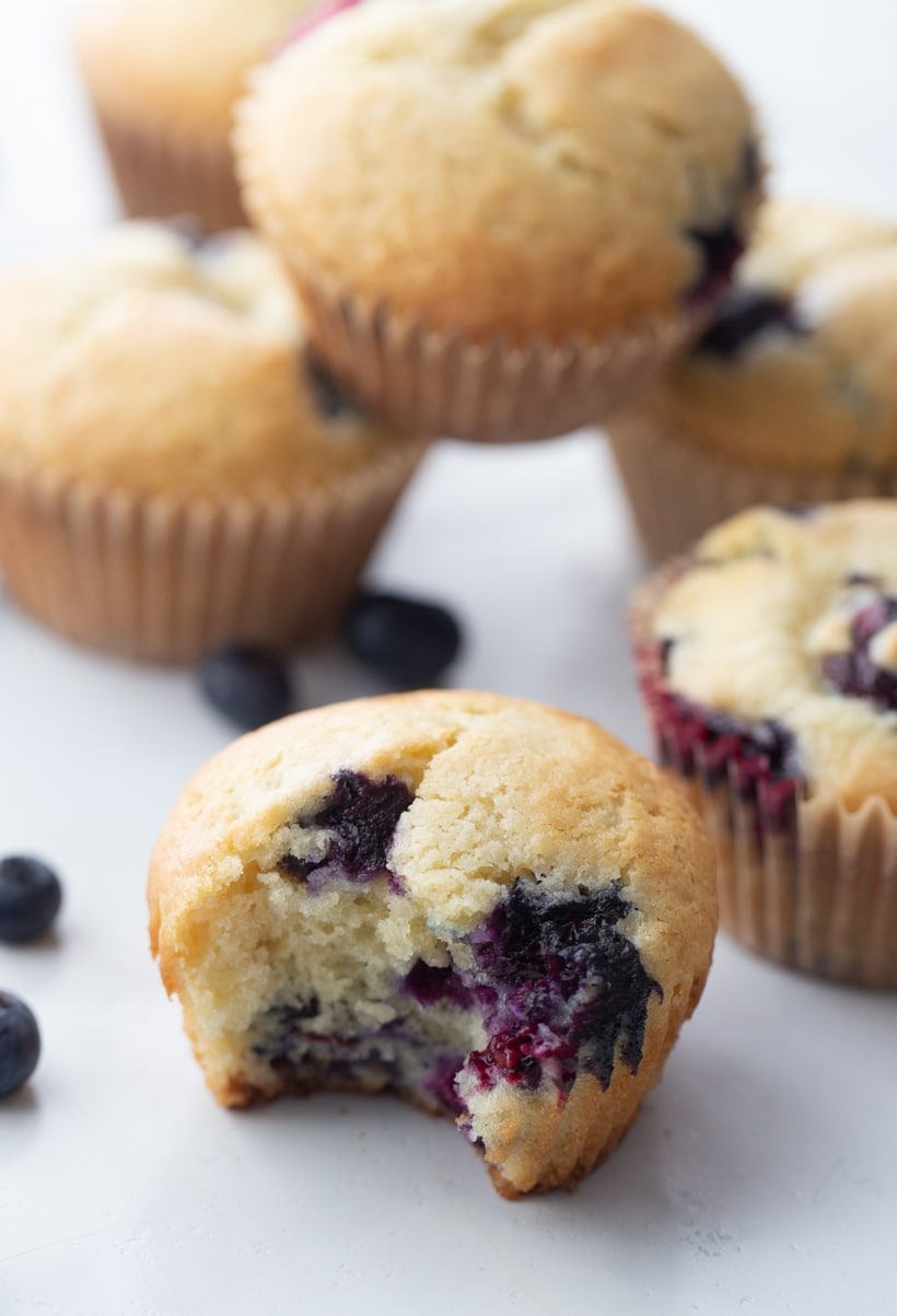 Sour Cream Blueberry Muffins on the counter sour cream blueberry muffins one bite removed