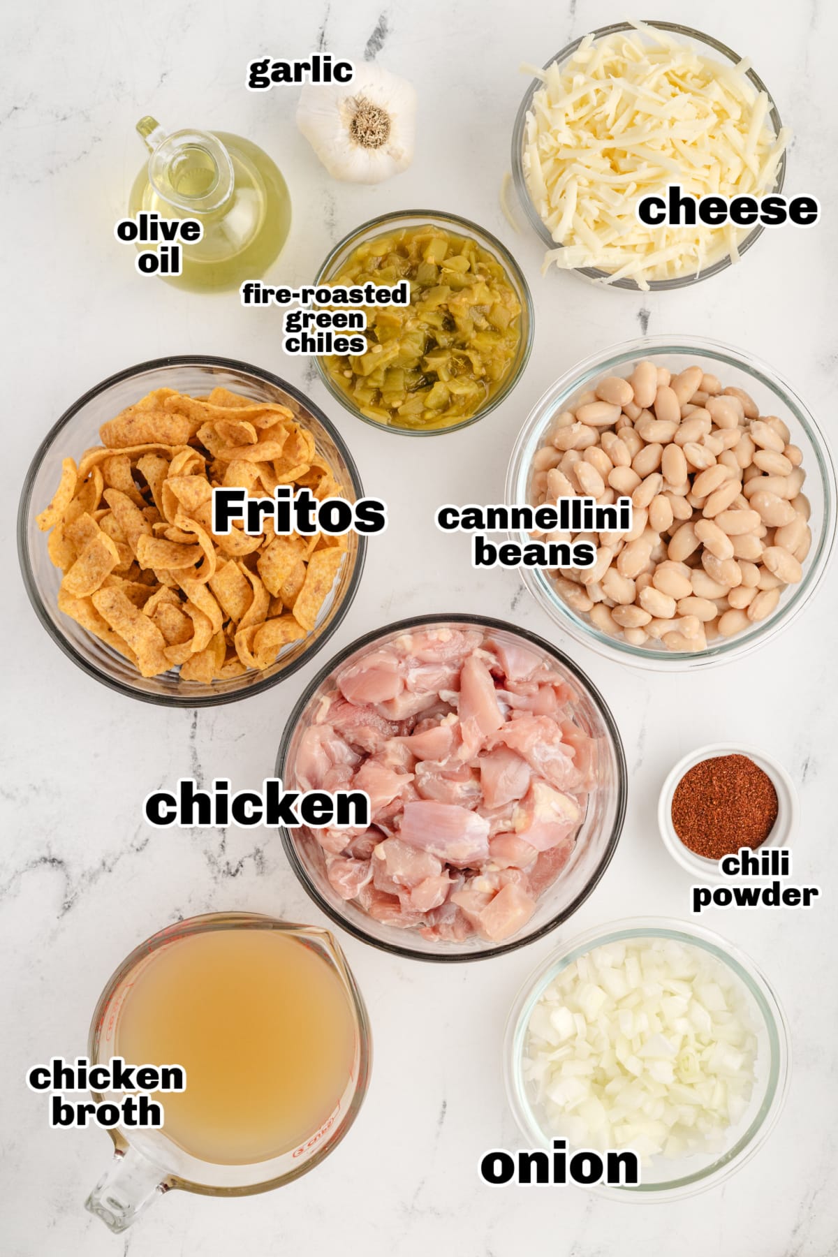 All ingredients for Chicken Frito Pie Casserole arranged on a countertop, including chicken, beans, green chiles, cheese, and Fritos.