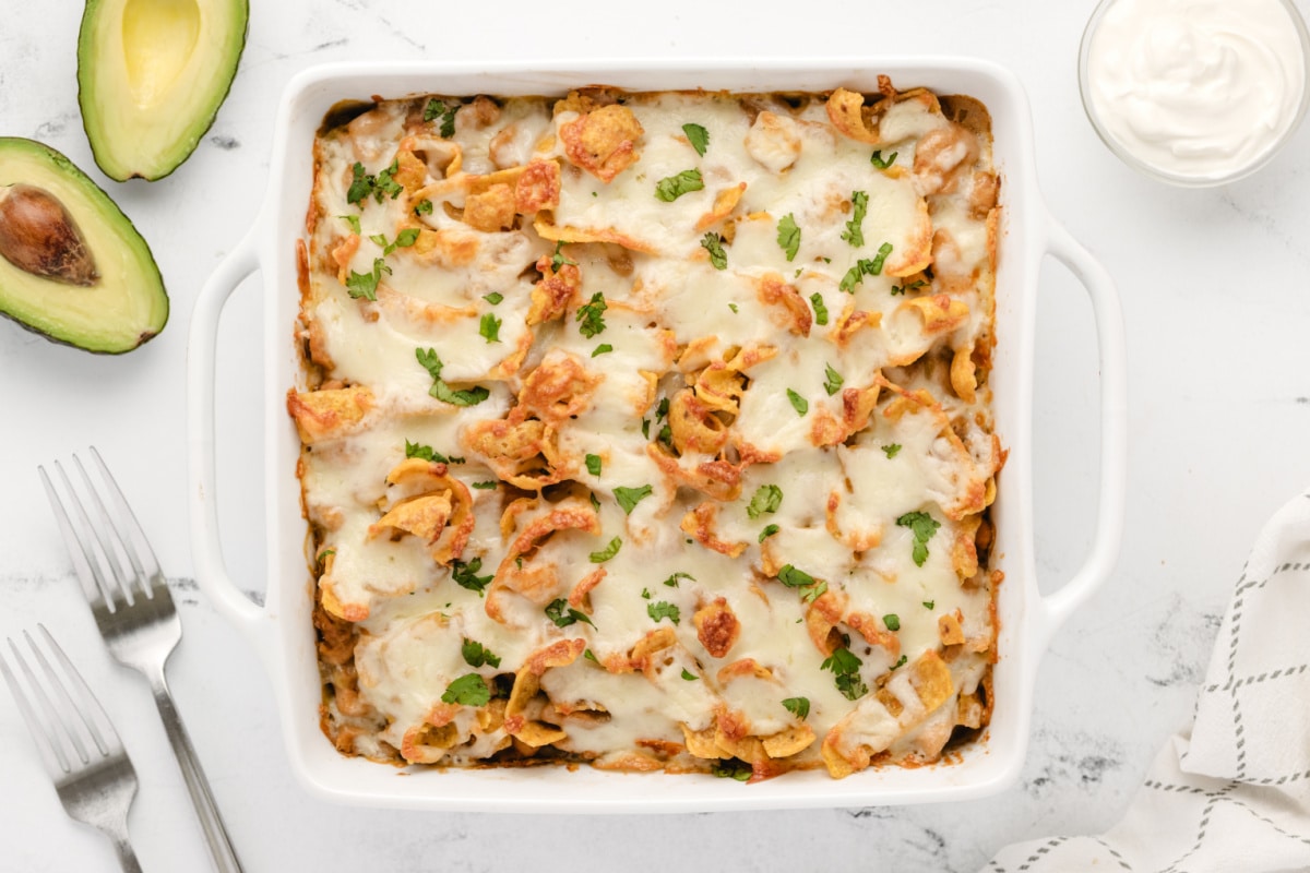 Top-down view of a full Chicken Frito Pie Casserole in a baking dish, topped with melted cheese and crunchy Fritos.