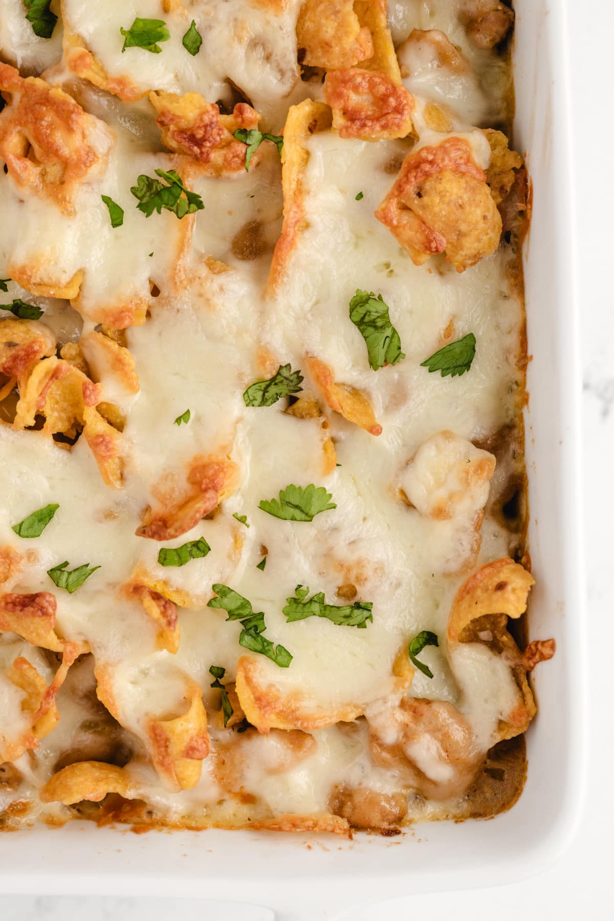 Close-up top view of a corner of the casserole, highlighting the melted cheese and golden Fritos on top.