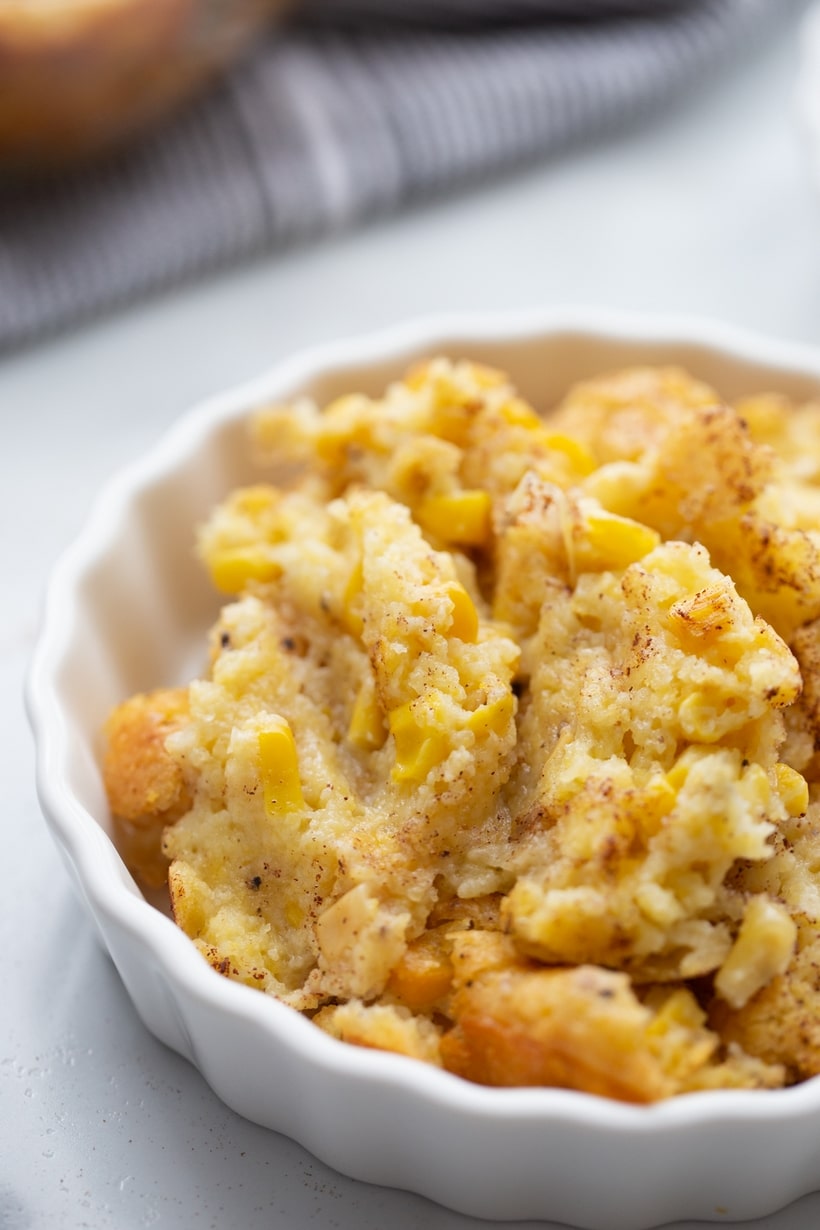Corn Pudding in a ramekin Side view of a ramekin filled with corn pudding, highlighting its creamy and spoonable texture.