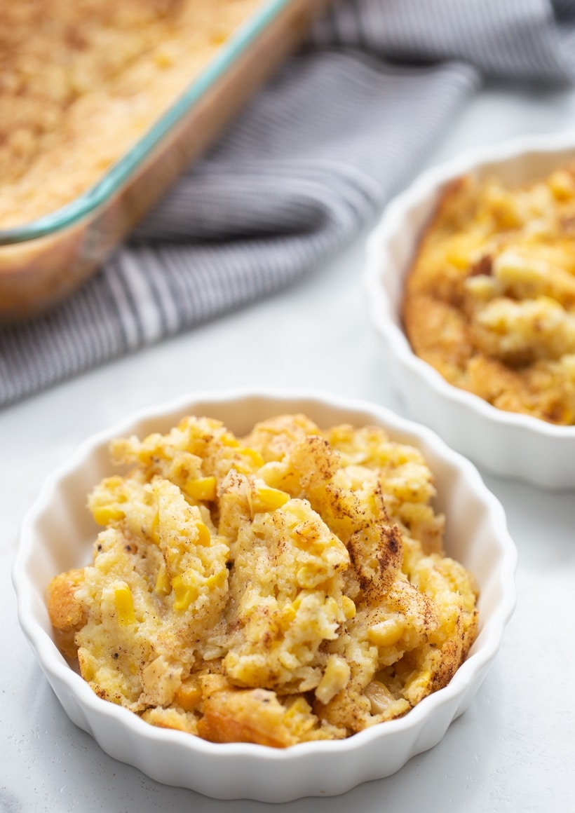 A serving of corn pudding Individual serving of corn pudding in a white fluted ramekin, showing its golden, slightly textured top.