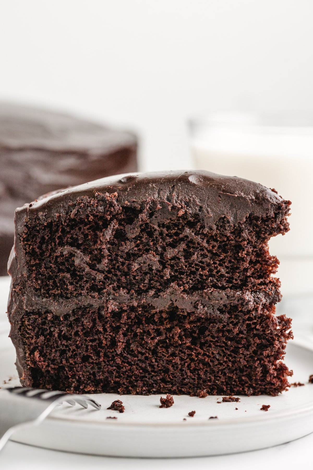 Old-Fashioned Chocolate Cake with Glossy Chocolate Icing on a plate Close-up of a sliced piece of old-fashioned chocolate cake on a plate, showing its moist layers and glossy chocolate icing.