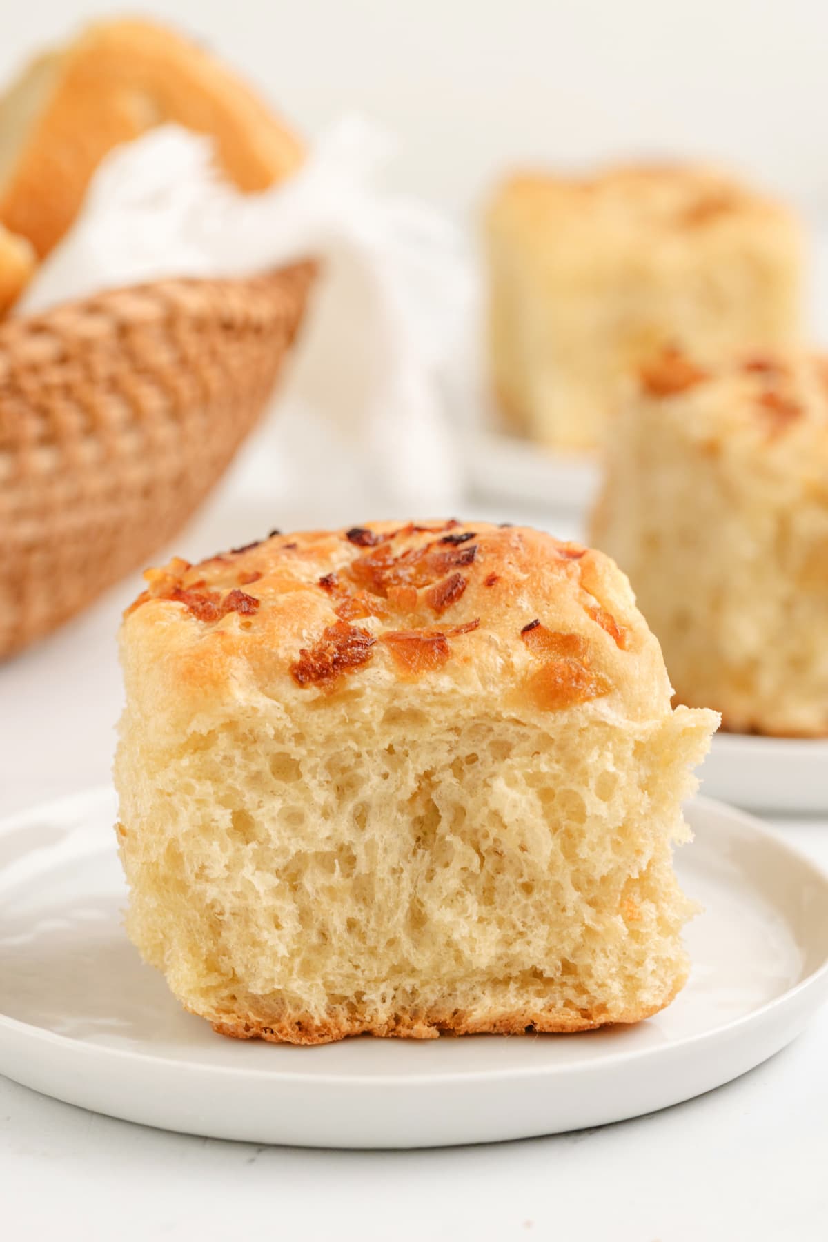 A soft, golden-brown onion roll with caramelized onions on top, showing its fluffy texture.