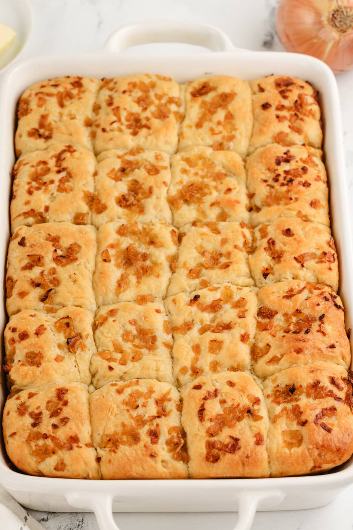 A full shot of a pan filled with golden, fluffy onion rolls, fresh from the oven.