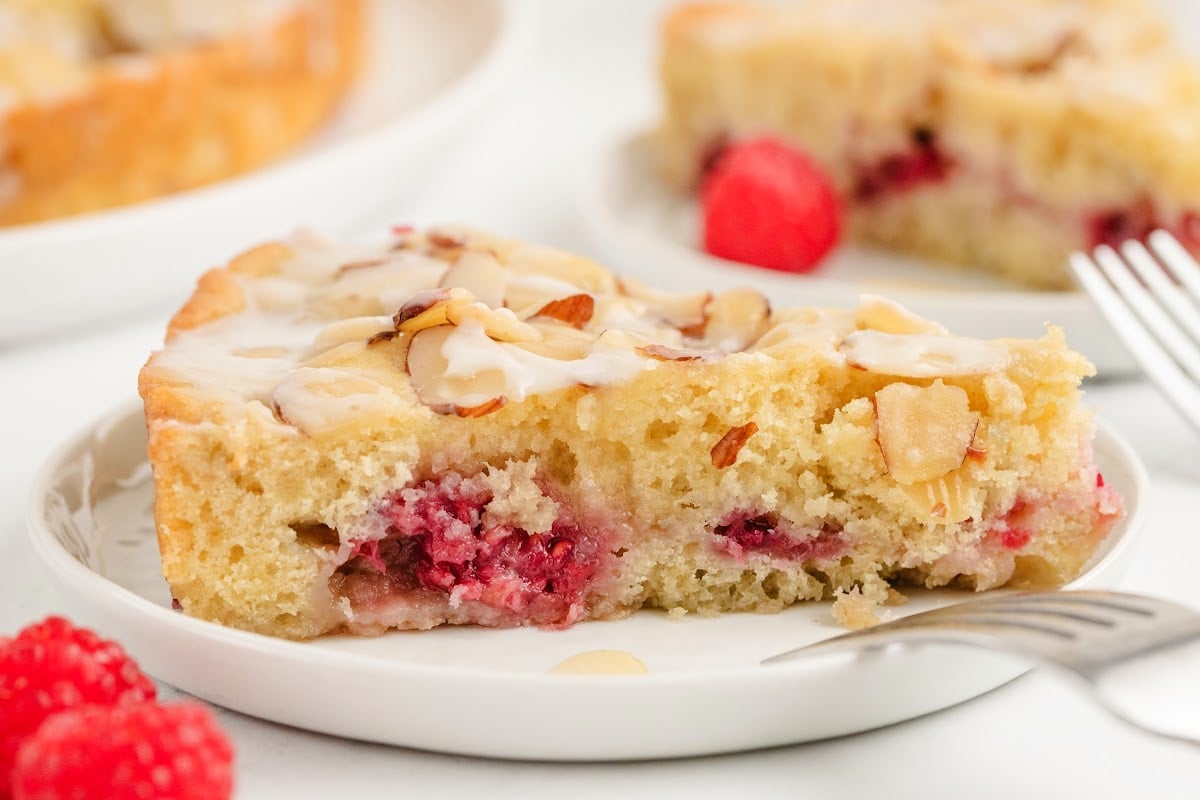 Raspberry Almond Coffee Cake one slice Side view of a full slice of raspberry almond coffee cake, highlighting the layers of tender cake, raspberries, and golden-brown almond topping.