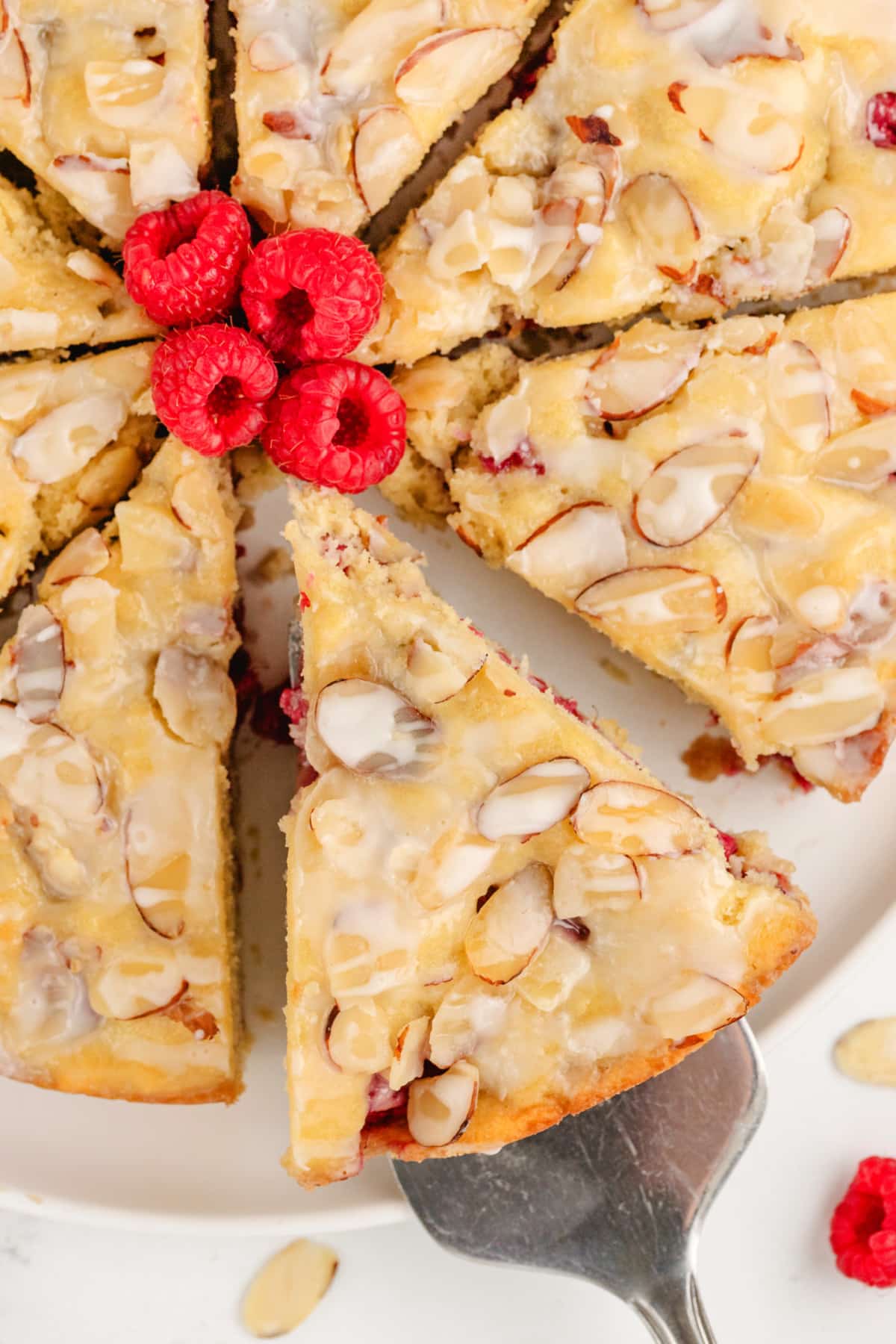 top view of Raspberry Almond Coffee Cake Top view of the full coffee cake after slicing, displaying the even slices and the contrast of the red raspberries against the golden cake.