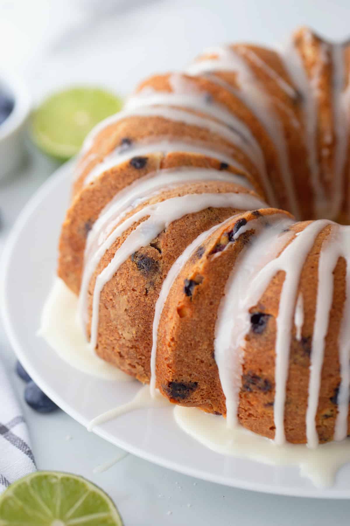 Glazed Blueberry-Lime Pound Cake Blueberry-lime pound cake on a plate, fully glazed with lime icing drizzled over the top and sides.