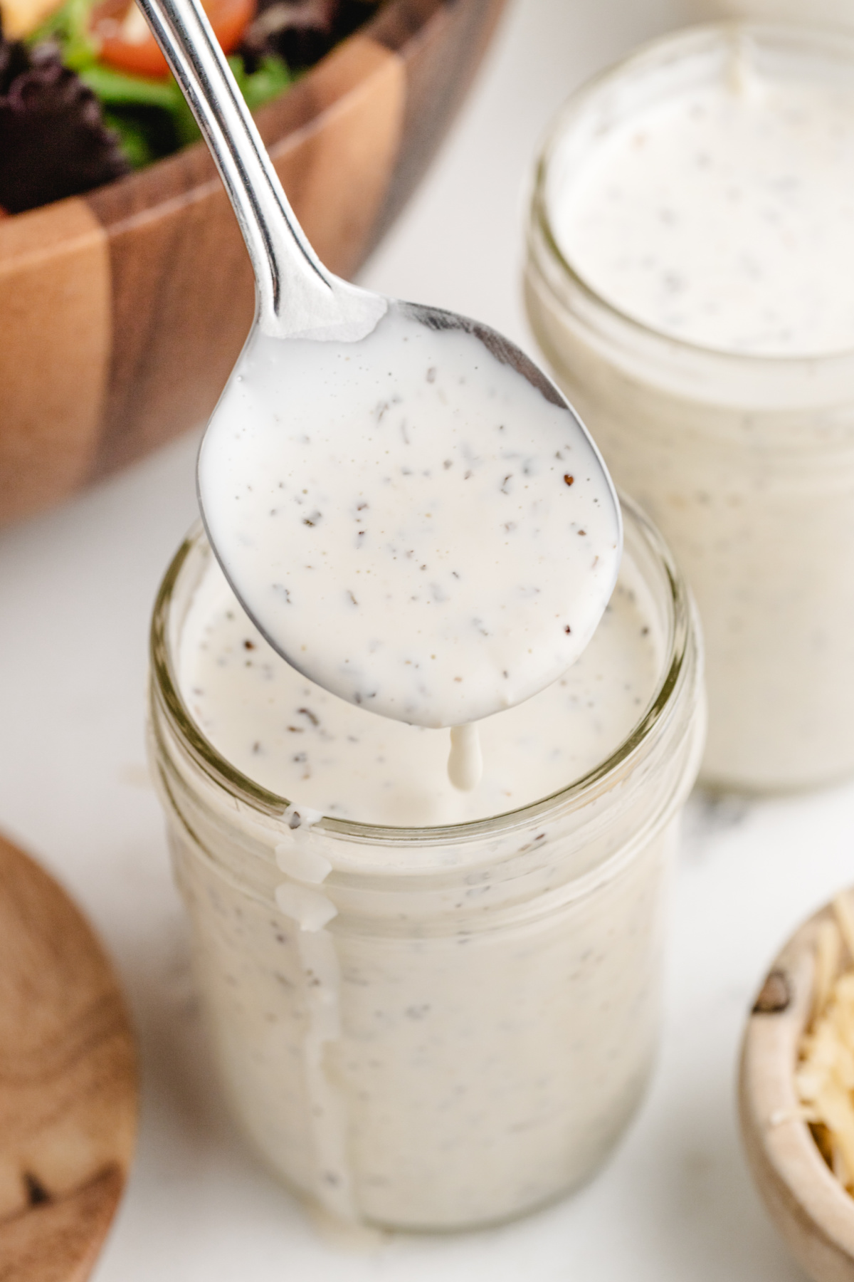 Homemade Creamy Pesto Dressing Like Spaghetti Factory Spoonful of creamy pesto dressing dripping back into jar