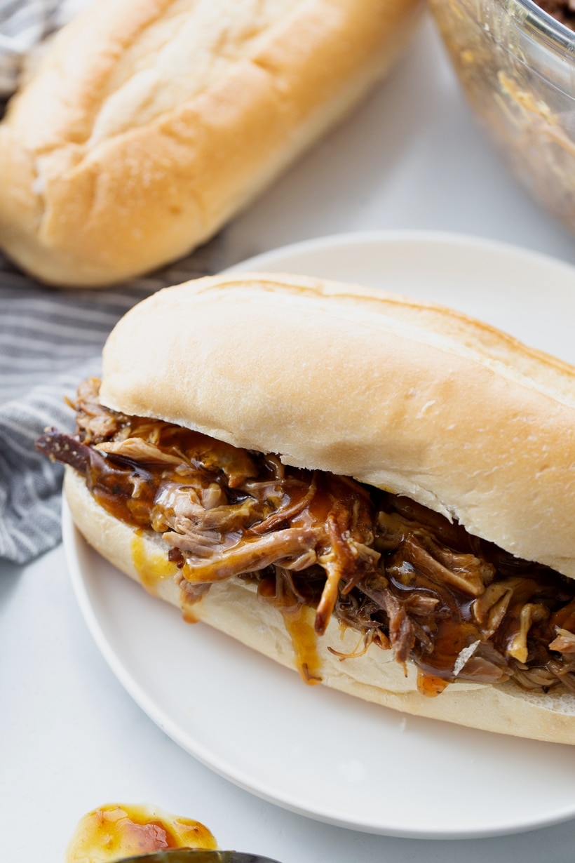 Slow Cooker Honey Soy Pulled Pork slow cooker honey soy pulled pork in a bun on a white plate
