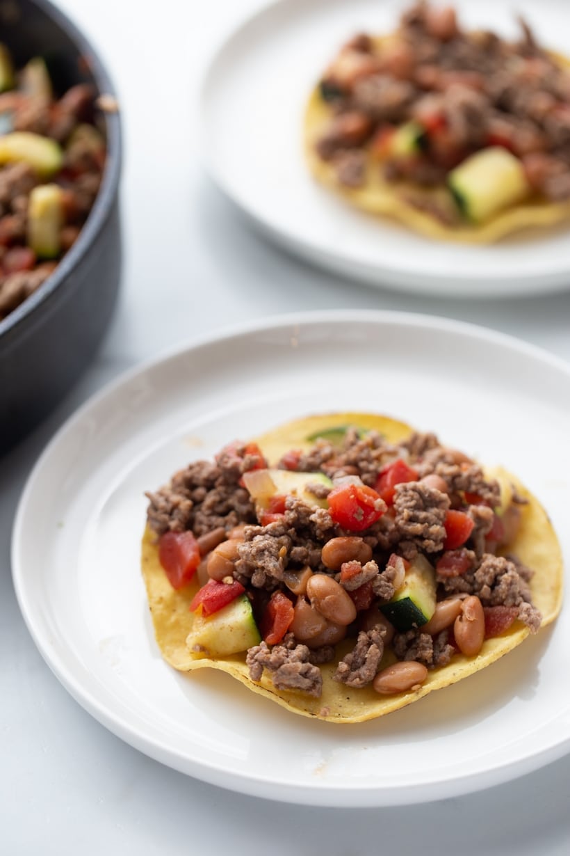 Starting tostada assembly with chipotle beef mixture on crisp shell