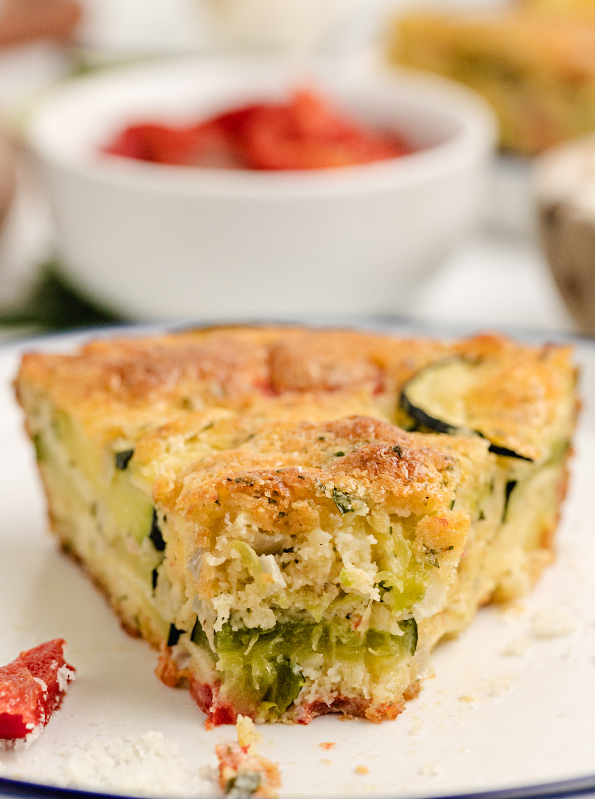 Bisquick zucchini bake slice with roasted peppers and cheese Close-up of a slice of crustless zucchini and red pepper pie with a golden, biscuit-like edge