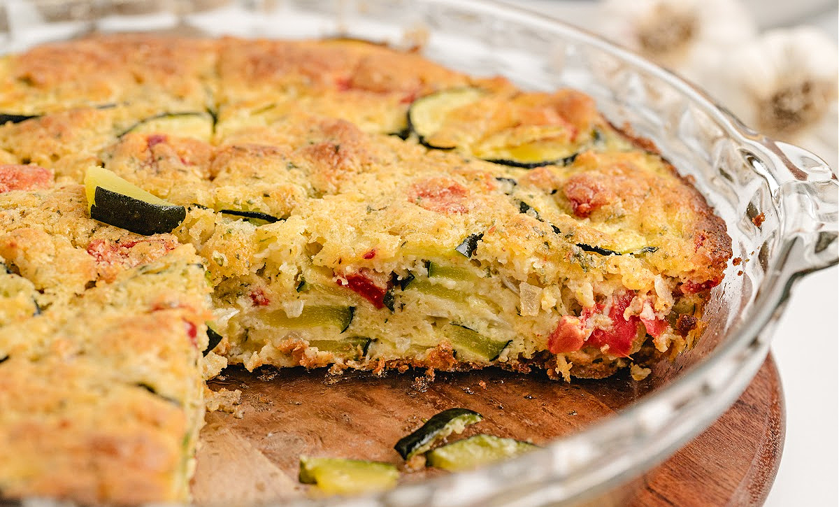 Crustless Bisquick zucchini pie with roasted red pepper and shallot Golden-baked zucchini pie in glass dish showing layers of vegetables and cheese