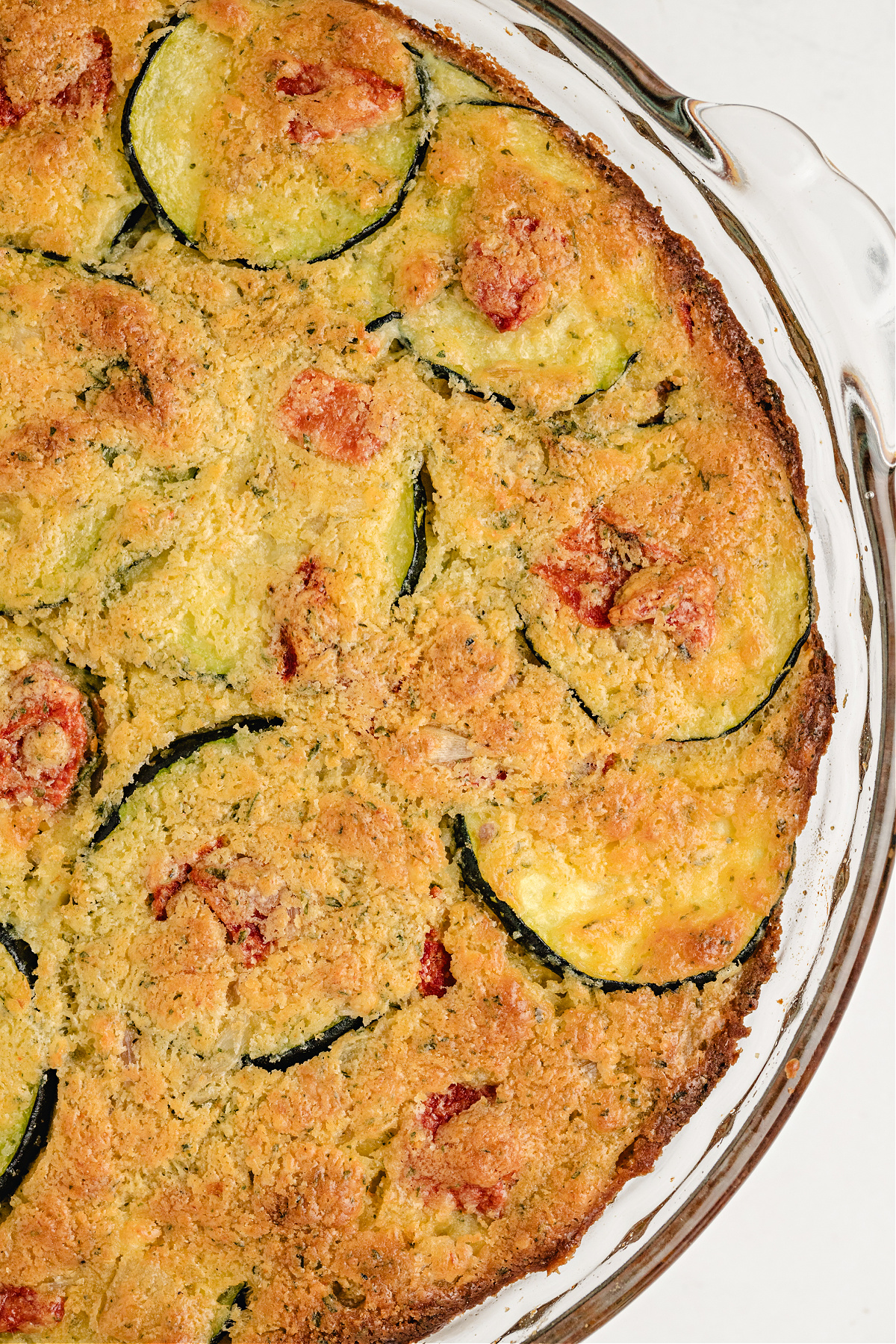 Savory zucchini bake with biscuit mix and roasted vegetables Close-up of golden top crust on zucchini biscuit mix pie with visible slices of squash and red pepper