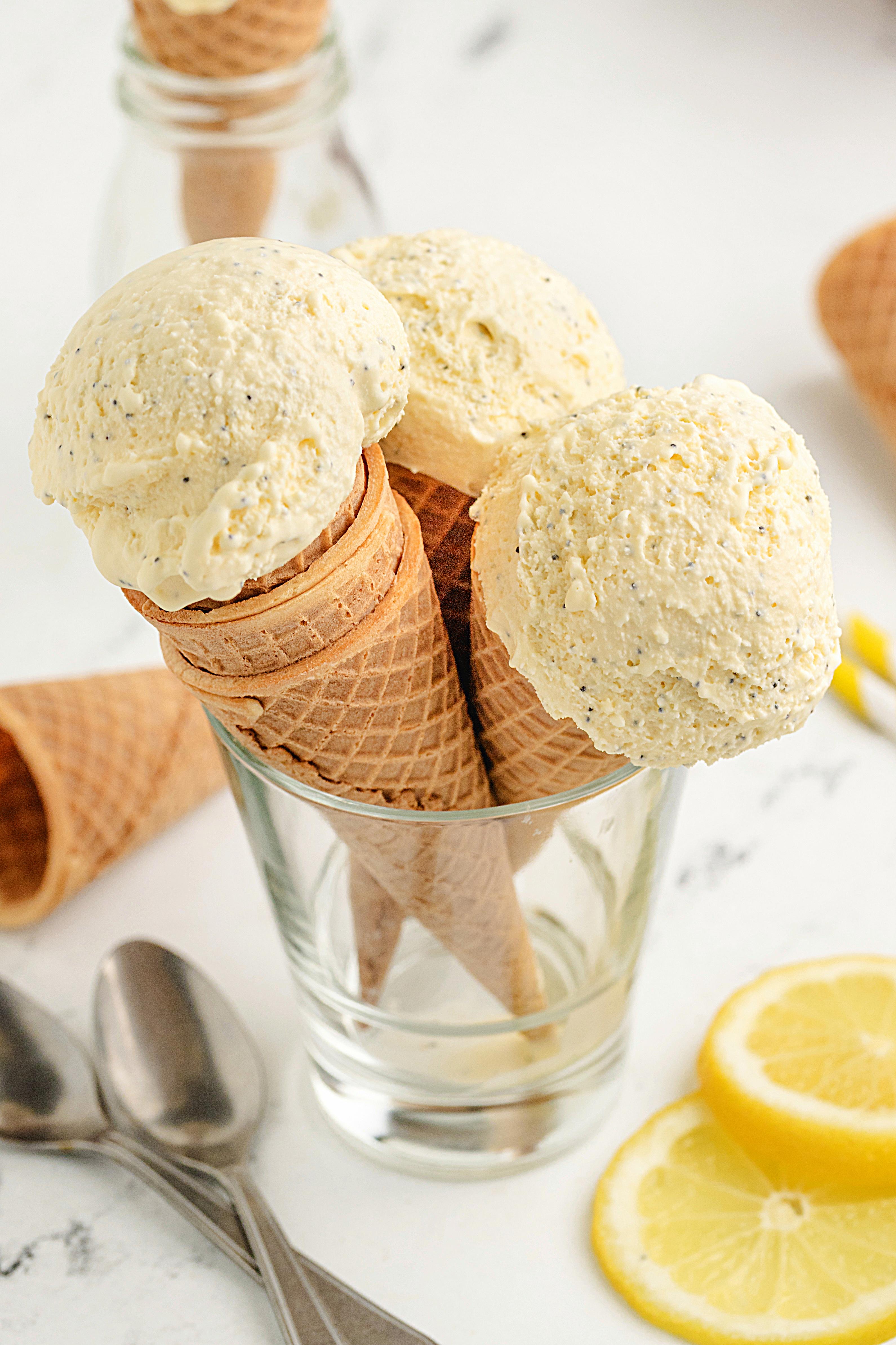 Homemade Lemon Poppy Seed Ice Cream in Waffle Cones Waffle cones filled with scoops of homemade lemon poppy seed ice cream in a glass