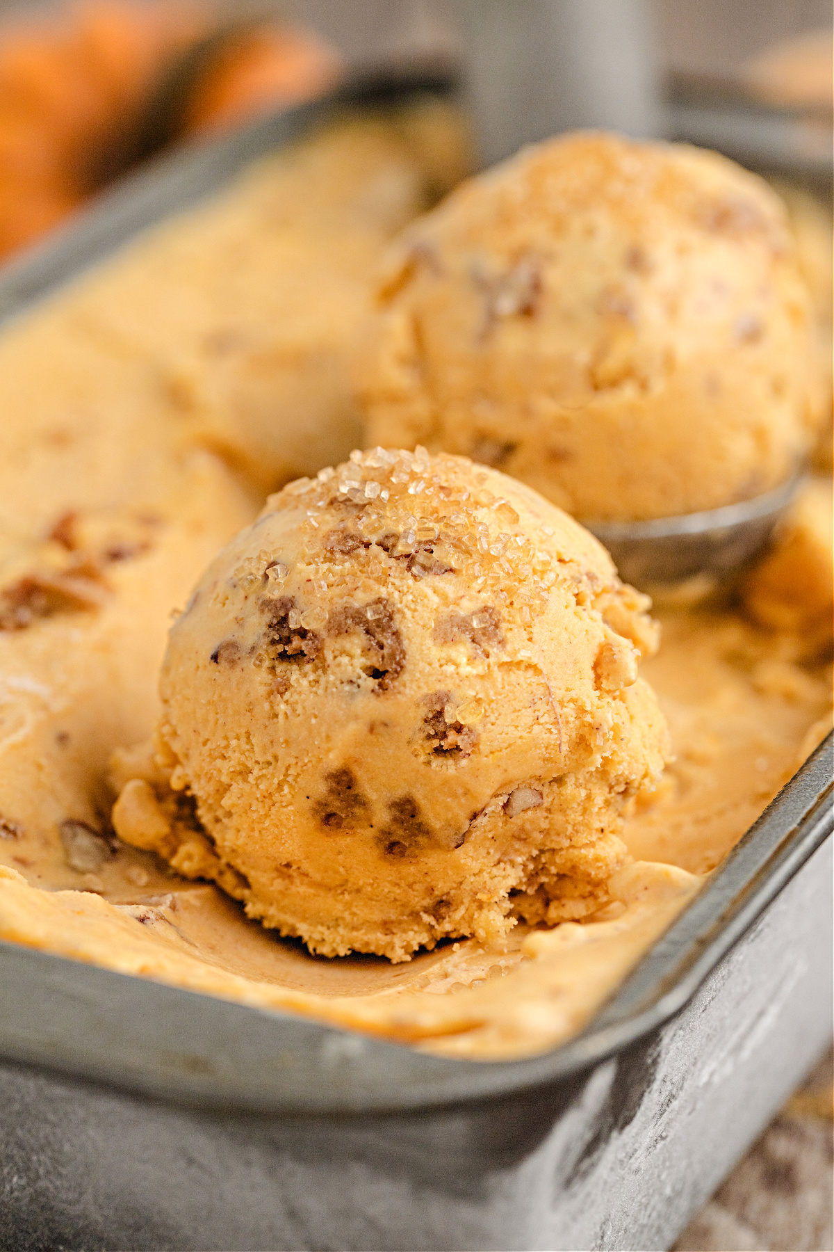 Close-up of Pumpkin Brown Sugar Crunch Ice Cream by Noble Pig, showing creamy scoops studded with pecan streusel and sprinkled with turbinado sugar for sparkle.