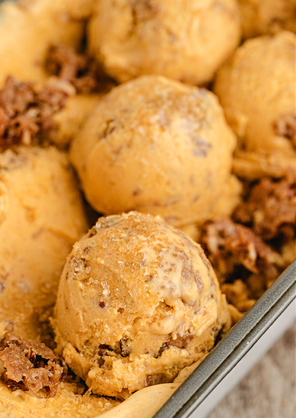 Close-up of Pumpkin Brown Sugar Crunch Ice Cream with pecan streusel and turbinado sugar on top, showing creamy pumpkin custard texture and buttery crunch.