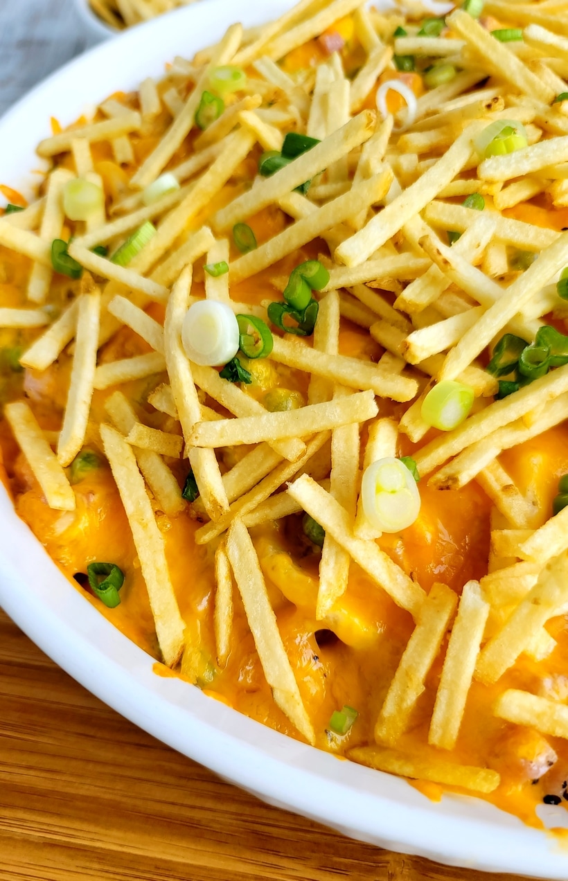 Close-up detail of the casserole topped with melted cheddar and chopped scallions for garnish.