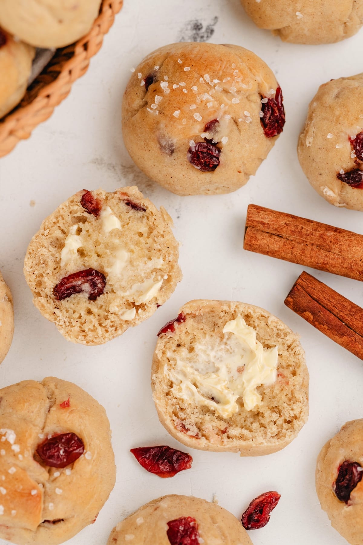Overhead shot of cinnamon-cranberry dinner rolls with buttered slice. Overhead view of cinnamon-cranberry dinner rolls, with one sliced open and topped with melted butter.
