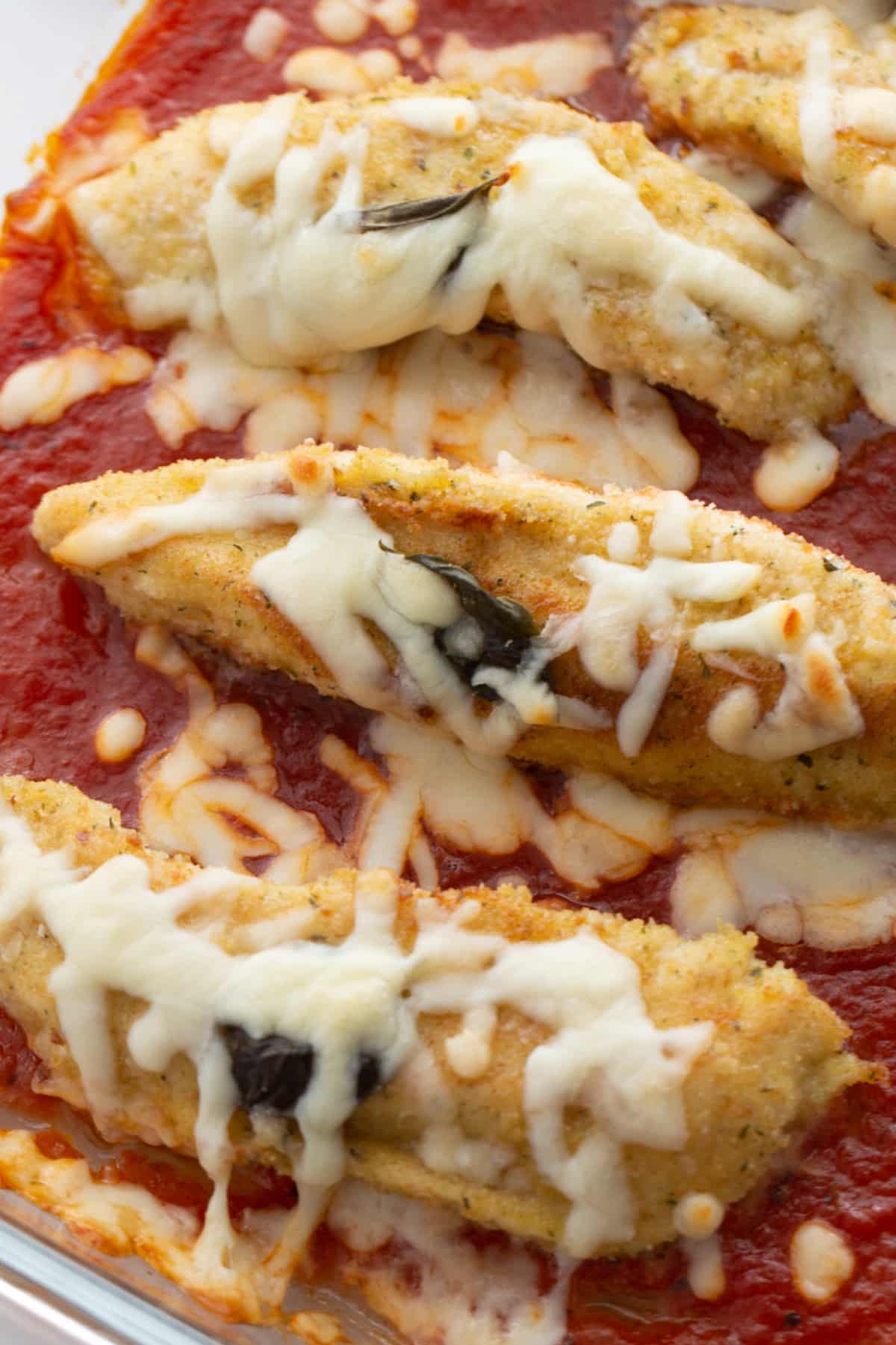 Baked chicken tenderloins with marinara and cheese Close-up of baked chicken tenderloins with melted mozzarella and marinara sauce
