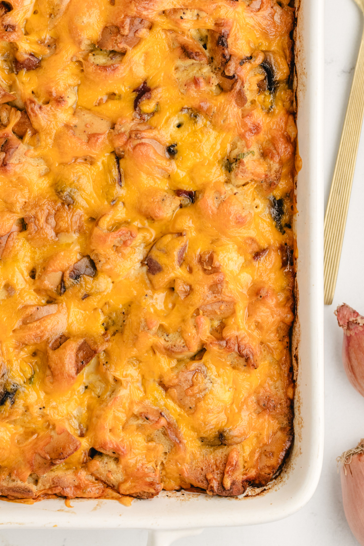 Cheesy overnight bagel breakfast casserole with kielbasa. Closeup of overnight breakfast casserole with bagels, kielbasa, and melted cheddar.