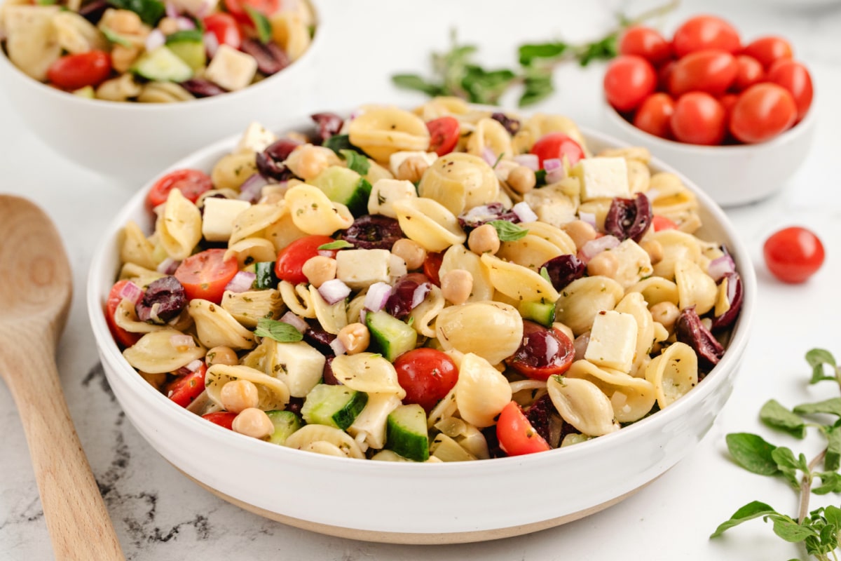 A close-up of the pasta salad, showing the textures of feta, chickpeas, and fresh veggies coated in dressing.