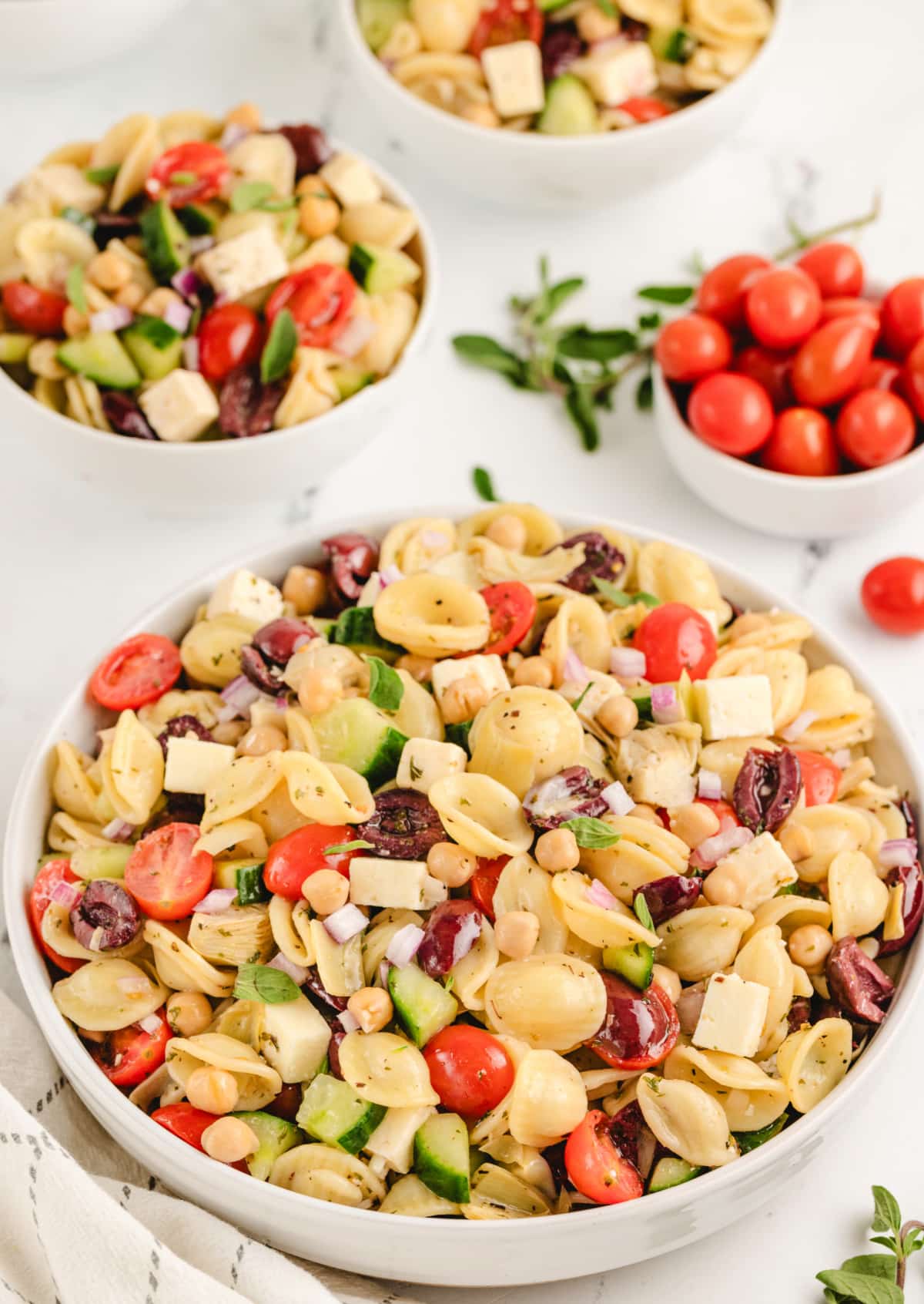 A bowl of Greek pasta salad with orecchiette, feta, olives, cucumbers, and tomatoes, tossed in a tangy dressing.