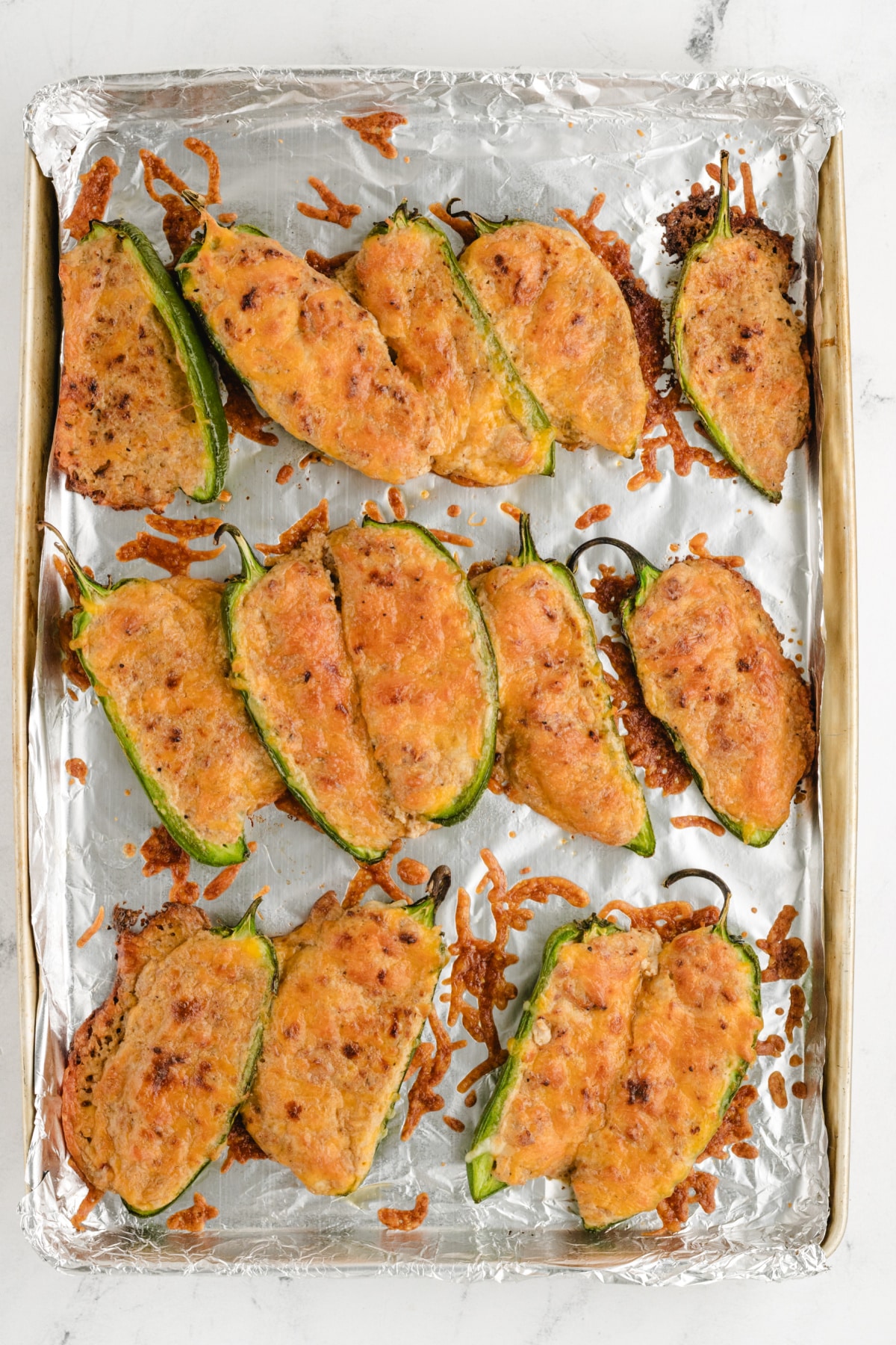 Freshly baked stuffed jalapeños arranged on a tray, showing the creamy, spicy filling.
