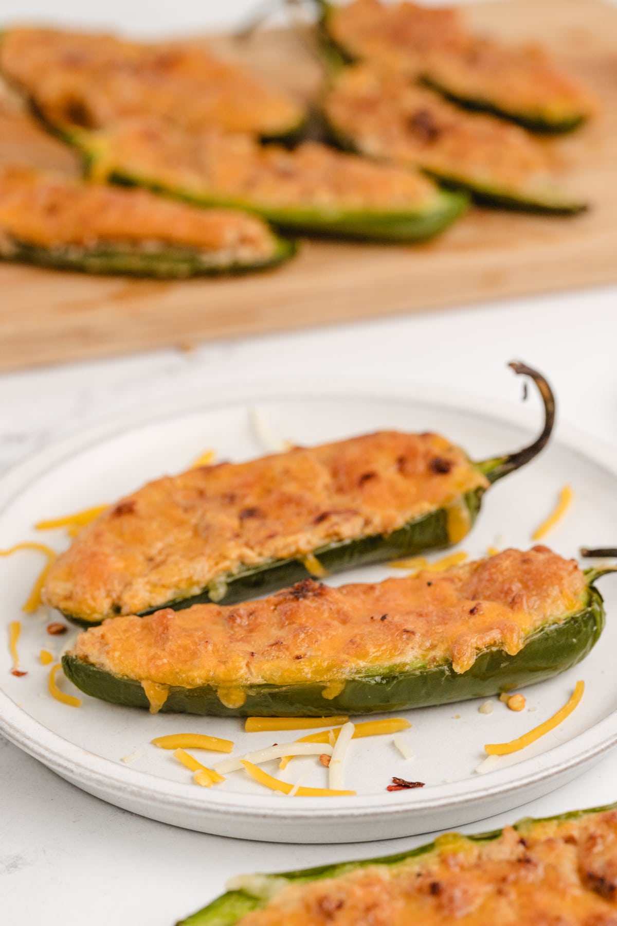 Ground turkey stuffed jalapeños on a plate with a crispy, bubbly cheese topping.