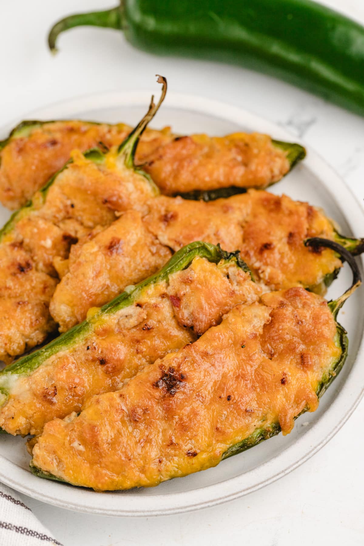 A plate of ground turkey jalapeños stuffed with seasoned turkey and cheese, highlighting the texture of the filling.