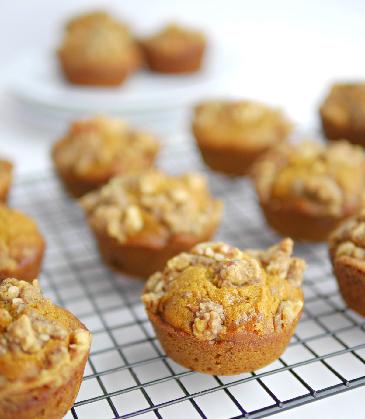 Freshly baked pumpkin spice muffins with brown sugar crumble cooling on a rack.