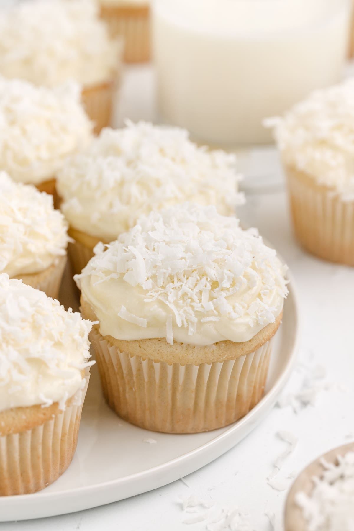Close-up of a coconut cupcake topped with coconut cream cheese frosting, showcasing the coconut flakes on top.