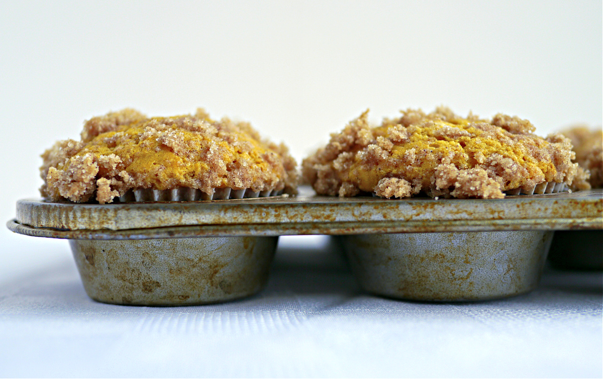 buttermilk pumpkin muffins with cinnamon streusel topping in striped liners on white surface