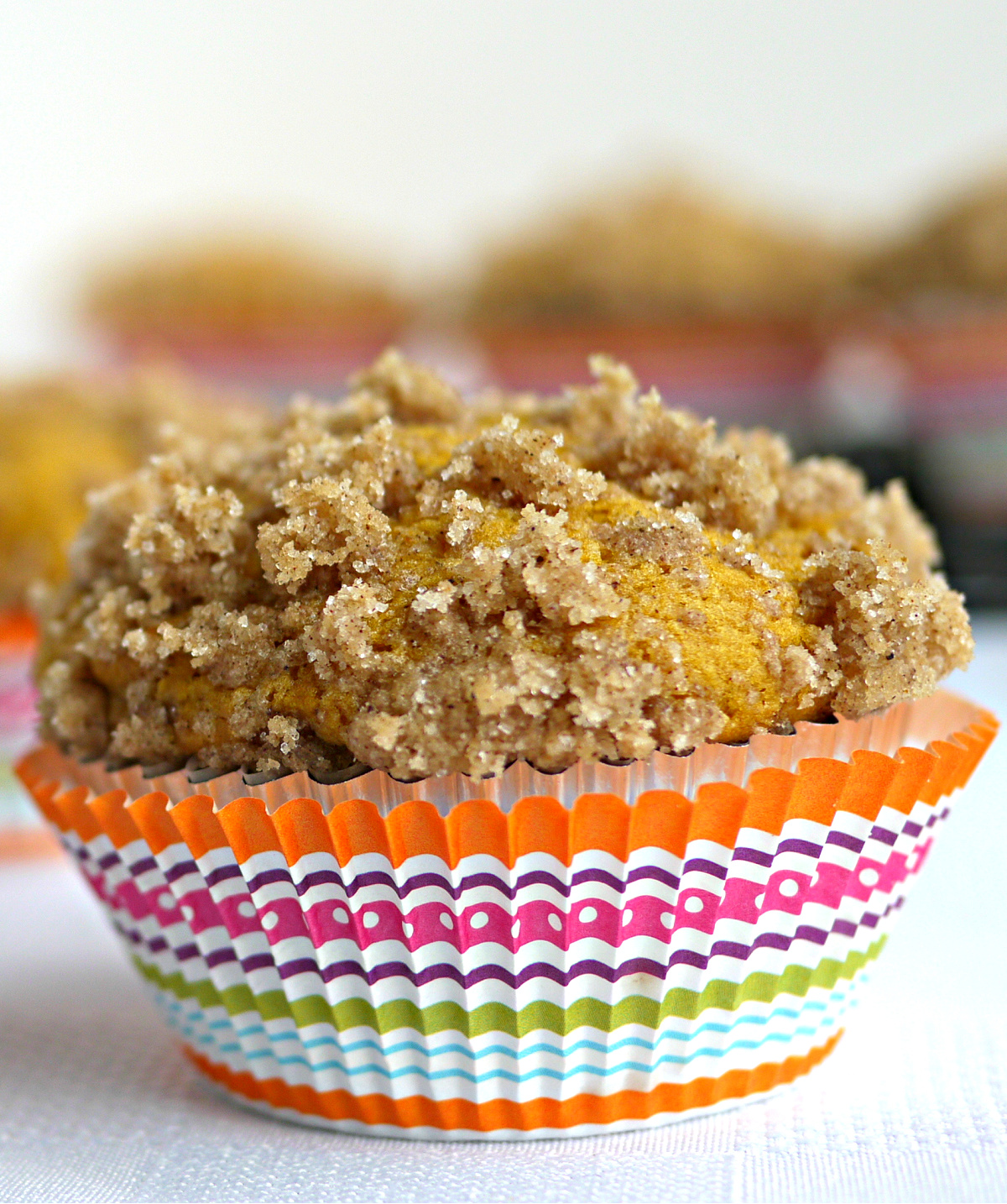 pumpkin buttermilk muffin with buttery streusel topping in a colorful striped liner